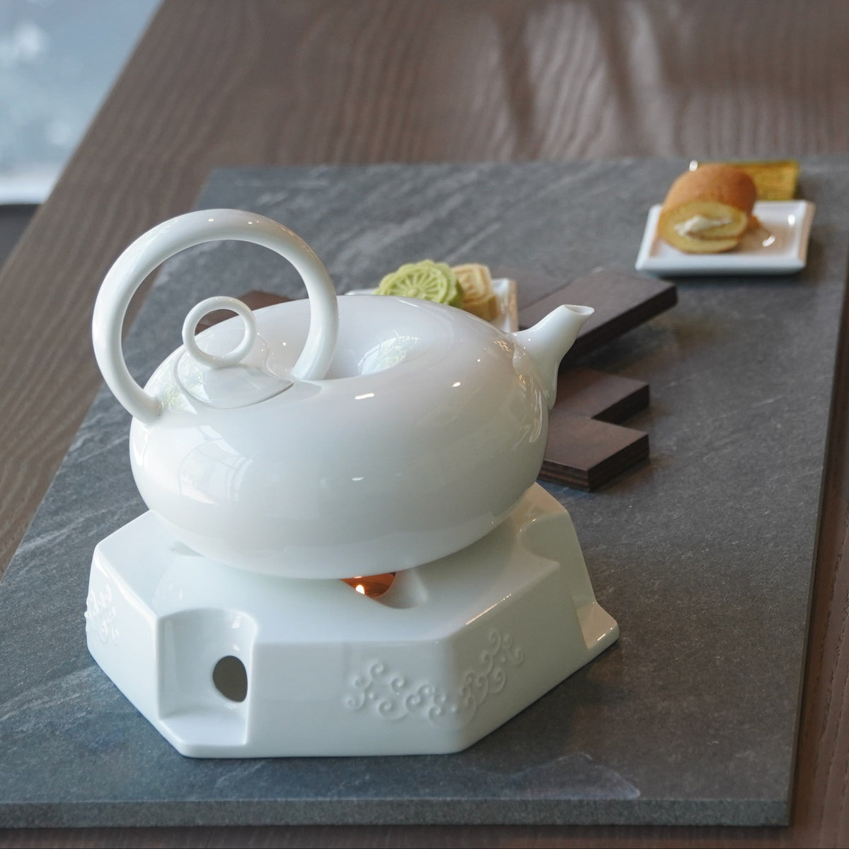 圓好夢白瓷茶具置於白色高台茶盤,搭配茶點與綠色背景形成品茶情境