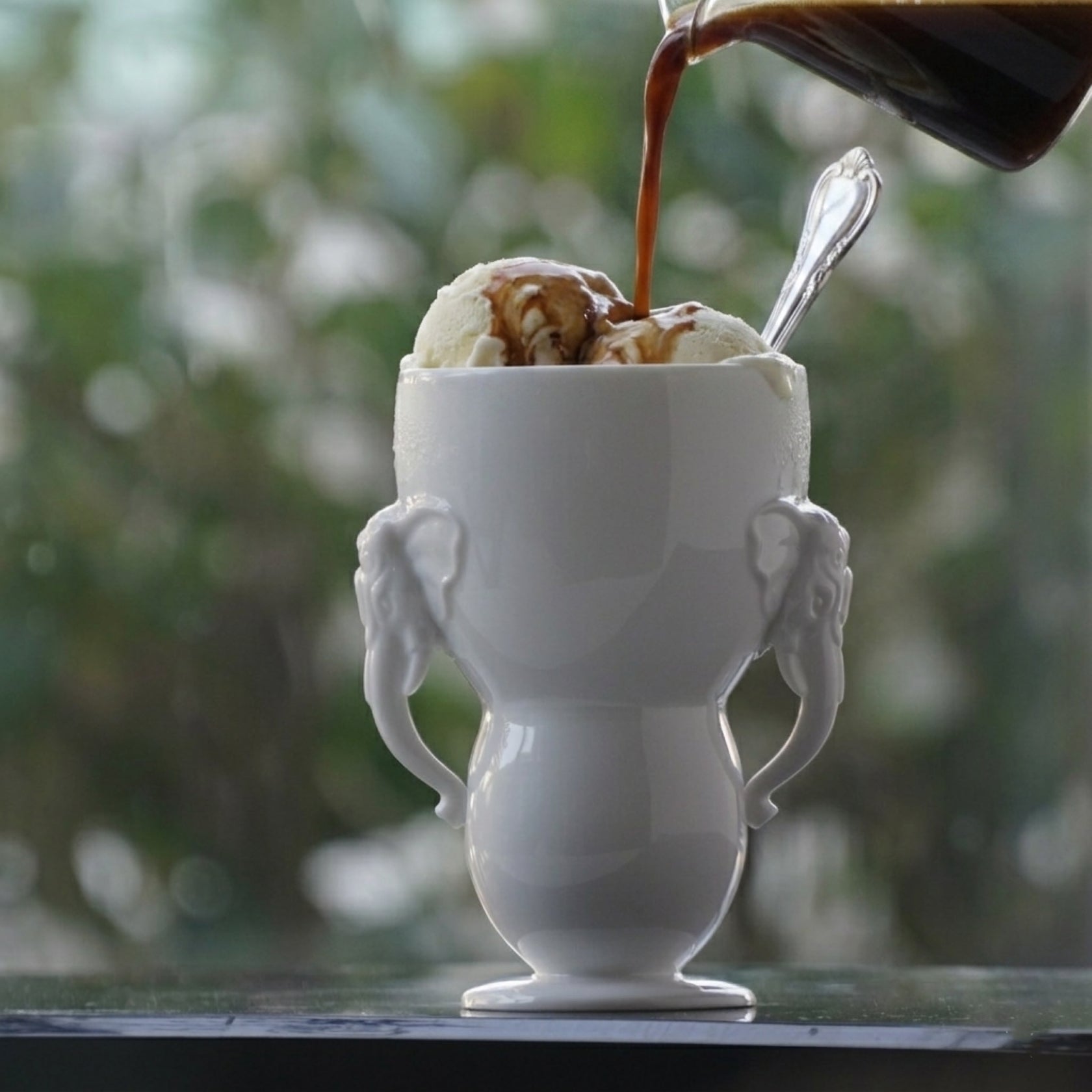 萬象一新精緻的雙象耳白瓷杯,完美盛裝上一份經典的義式甜點 Affogato(阿芙佳朵)濃郁、高溫的 Espresso 緩緩澆淋在冰涼細緻的香草冰淇淋上,沿著瓷器優雅的弧度流淌,展現出冷與熱、黑與白的極致交融。