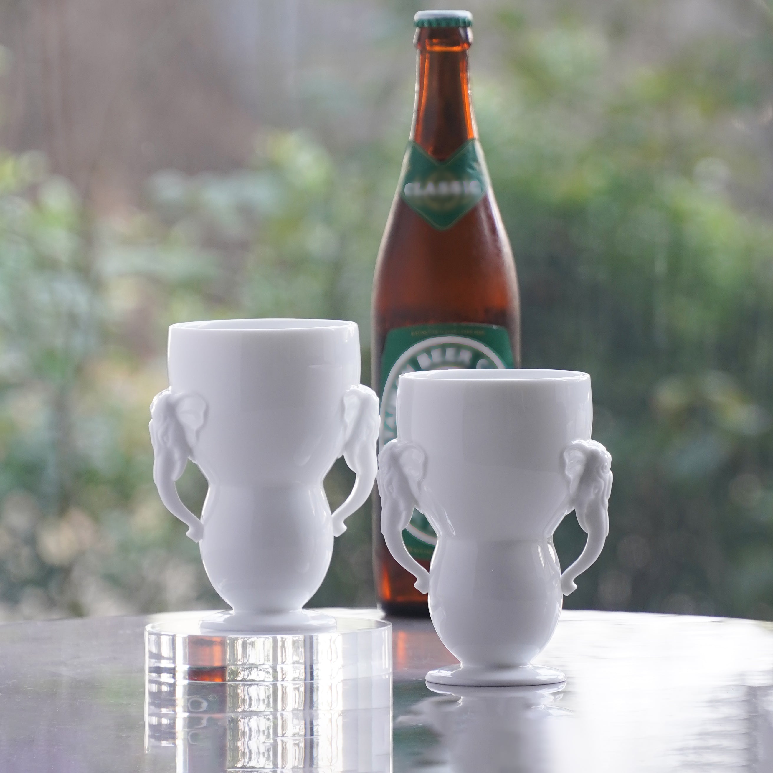 萬象一新白瓷大象把手杯與啤酒瓶搭配,展示以白瓷杯飲啤酒使用情境,八方新氣