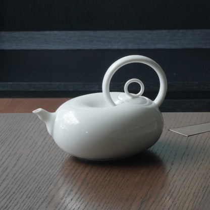 圓好夢白瓷茶壺側面特寫，渾圓壺身、短壺嘴與高揚環形把手清楚可見