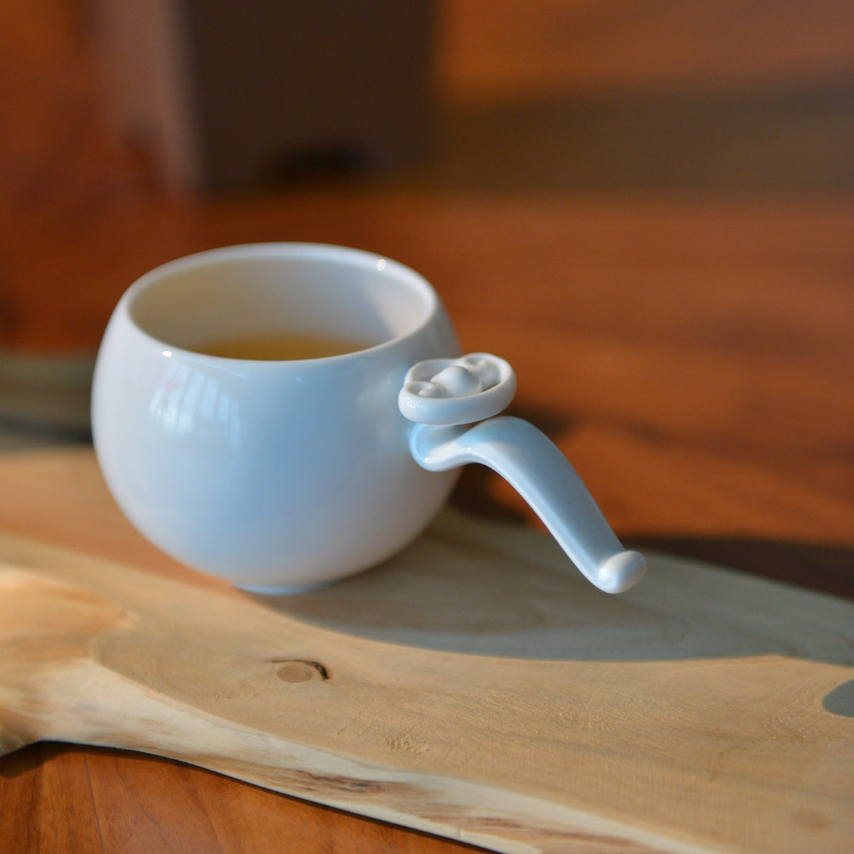 〈如意高飛〉茶杯盛茶，杯把如意紋